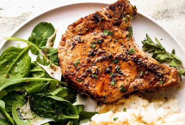 Oven-baked bone-in pork chops fresh out of the oven, seasoned and ready to serve